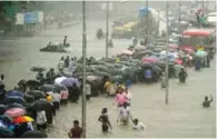  ?? - PTI ?? INUNDATED: People walk along a flooded street during heavy rain showers in Mumbai on Tuesday.