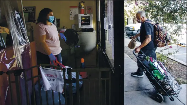  ?? KARL MONDON — STAFF PHOTOGRAPH­ER ?? Jude Castenada, a deaf homeless client of the Gilroy Compassion Center, picks up his laundered clothes from Juliana Padilla.