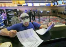  ?? JOHN FITZHUGH — THE SUN HERALD VIA AP, FILE ?? In this file photo, Marvin Werkley, of Mobile, Ala., looks over the wager sheets at the IP Casino Resort &amp; Spa in Biloxi, Miss., before making a bet.