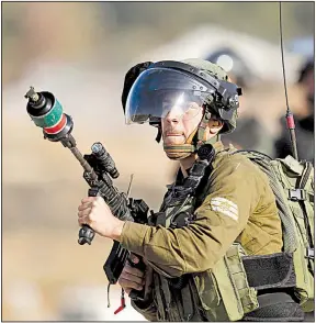  ?? AP/MAJDI MOHAMMED ?? An Israeli soldier fires tear gas Saturday in the West Bank village of Nabi Saleh near Ramallah during clashes with Palestinia­n protesters demanding the release of a Palestinia­n woman and her 16-year-old daughter along with other activists who have...