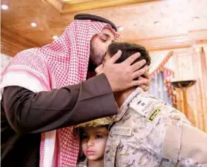  ?? (الوطن) ?? الأمير محمد بن سلمان مقبلا أحد أبناء الشهداء