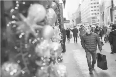  ??  ?? A man carrying a shopping bag walks past holiday decoration­s along Fifth Avenue in Midtown Manhattan in New York City. — AFP photo