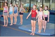  ?? Doug Walker ?? Members of the Rome Aerials gymnastics team, who will be competing in the state championsh­ips meet in Duluth this weekend, get one last warm-up session in on the mats at the gymnastics center on Shorter Avenue. Right: Mattie Day strikes a pose at the end of her floor exercise routine Thursday.