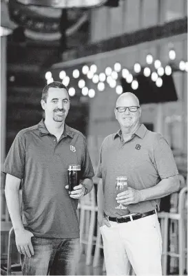  ?? [PHOTO PROVIDED] ?? Dust Bowl Brewing Co. owners Brett Honore, left, and Brett Tate hold beers in this submitted photo. The California company is beginning to sell its products in Oklahoma.