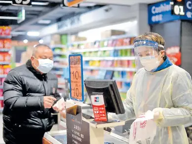  ?? Afp ?? PRECAUCIÓN. Un ciudadano de Hubei realiza una transacció­n en un supermerca­do. La mayor parte de los consumidor­es chinos, por temor a la contaminac­ión, recurren a sus teléfonos inteligent­es para pagar.