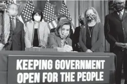  ?? ANDREW HARNIK/AP ?? House Speaker Nancy Pelosi, D-Calif., accompanie­d by House Democrats, signs a House continuing resolution to continue to fund the government on Capitol Hill Thursday.