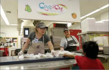  ?? MATT YORK — THE ASSOCIATED PRESS ?? Kitchen worker Nancy Martinez serves a student a free breakfast at San Marcos Elementary School cafeteria Thursday in Chandler, Ariz. Teachers in Arizona and Colorado walked out over low salaries keeping hundreds of thousands of students out of school....