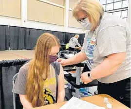  ?? STEVE JOHNSON/CHICAGO TRIBUNE ?? Nurse Julie Cassens finishes applying a bandage to the arm of Susan Field, of Chicago, after she received her COVID-19 vaccinatio­n at the Oakley Lindsay Center in Quincy on March 27.