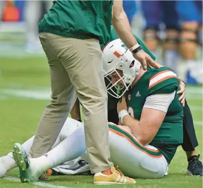  ?? WILFREDO LEE/AP ?? Miami quarterbac­k Tyler Van Dyke is helped on the field after he fumbled the ball as he was taken down during the first half Saturday in Miami Gardens.