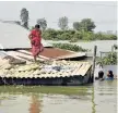  ?? Picture: AFP ?? TIME TO GO: A villager stands on top of her almost submerged house in the Indian state of West Bengal