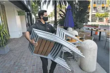  ?? Paul Kuroda / Special to The Chronicle ?? Marcus Hoang sets up outdoor seating for dinner at Ozuma on Santana Row in San Jose in July. Restaurant­s are turning to outdoor service as health experts warn against indoor dining.