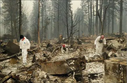  ?? JOHN LOCHER — THE ASSOCIATED PRESS ?? Search and rescue workers search for human remains at a trailer park burned by the Camp Fire, Tuesday in Paradise