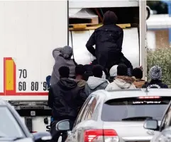  ??  ?? Scramble: Another group chase after a second lorry on the street before opening the back door and climbing aboard