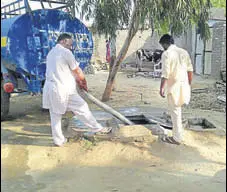 ?? HT PHOTO ?? Residents filling up an undergroun­d storage tank with water from a tanker at Maan village in Muktsar district on Monday.