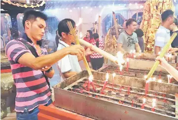  ??  ?? Devotees burn incense for the offering.