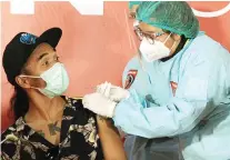  ?? MIFTAHULHA­YAT/JAWA POS ?? NGGAK SAKIT, KOK: Akhadi Wira Satriaji alias Kaka Slank disuntik vaksin Covid-19 di Jakarta kemarin (19/4).