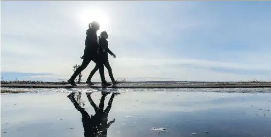  ?? LYLE ASPINALL ?? People walk past a puddle during a chinook last February in Calgary. The hot air that followed Donald Trump’s U.S. election win heated up the markets, writes Martin Pelletier.