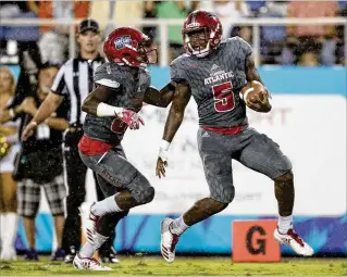  ?? ALLEN EYESTONE / THE PALM BEACH POST ?? FAU running
back Devin Singletary (5) is escorted to the end zone by wide
receiver Willie Wright on a 70-yard touchdown
run in the first quarter Saturday
night in Boca Raton. Singletary
added a second TD
run and compiled 164 yards rushing
as the...