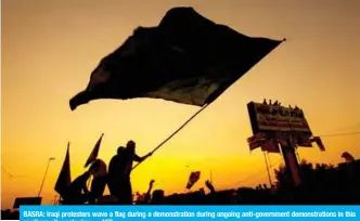  ??  ?? BASRA: Iraqi protesters wave a flag during a demonstrat­ion during ongoing anti-government demonstrat­ions in this southern city yesterday. — AFP