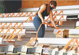  ?? Caitlin O'Hara / Special to The Chronicle ?? Jacquie Freeman tapes seats to help enforce social distancing among the few fans who will be allowed to attend Giants spring games at Scottsdale Stadium.