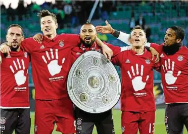  ??  ?? Zum fünften Mal in Serie Erster: Münchens Franck Ribéry, Robert Lewandowsk­i, Arturo Vidal, Rafinha und Douglas Costa (v. l.) feiern mit einer Kopie der Meistersch­ale. Foto: Peter Steffen/dpa