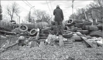  ?? AP/IGOR GOLOVNIOV ?? A man stands on a barricade Saturday at a Ukrainian regional Security Service office in Luhansk, about 20 miles west of the Russian border, as pro-Russian groups seized offices in Donetsk and Slovyansk in eastern Ukraine.