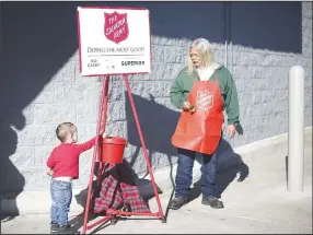  ?? (NWA Democrat-Gazette/Charlie Kaijo) ?? Bryce Fontenot (left), 2, of Bentonvill­e makes a donation Monday as volunteer Kevin Schrand rings a bell at the Walmart Super Center in Bentonvill­e. Check out nwaonline.com/211214Dail­y/ for today’s photo gallery.