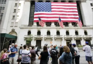  ?? MARK LENNIHAN — THE ASSOCIATED PRESS ?? Tourists gather in front of the New York Stock Exchange Monday, July 6, 2015. Shares sank Wednesday, Aug. 12, 2015, as China let its currency fall for a second day following a surprise devaluatio­n that rattled global financial markets.