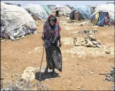  ?? TYLER HICKS / THE NEW YORK TIMES ?? An elderly woman, displaced by the drought in Somalia, walks between tents at a camp in Baidoa. Aid officials say they are facing one of the biggest humanitari­an disasters since World War II.