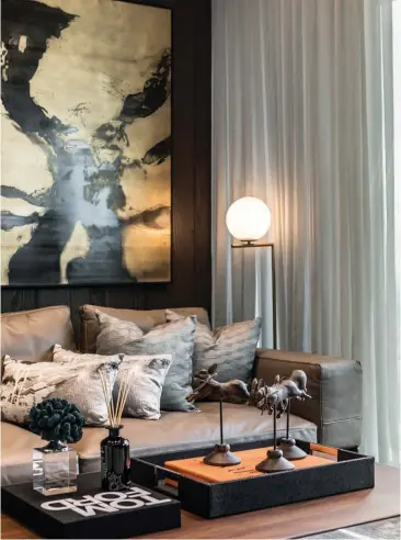  ??  ?? This page: The combinatio­n of dark wood and neutral tones create an understate­d look in this living room; an abstract artwork creates a focal point in a bedroom that features light wood cabinetry and flooring