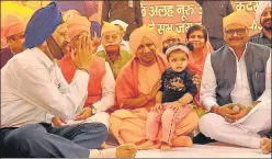  ??  ?? ■
Chief minister Yogi Adityanath holds a child during the Prakash Parv celebratio­ns and (below) people enjoying ‘langar on the DAV College premises in Lucknow on Tuesday.