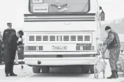  ?? ARTUR LEBEDEV/THE ASSOCIATED PRESS ?? A police officer with a sniffer dog and security guards check a bus entering the Olympic Park in Sochi. Russian sports officials said this week they will beef up security.