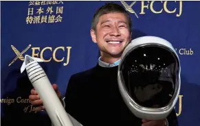  ?? — AFP ?? Skyward bound: Maezawa posing with a miniature rocket and space helmet prior to the start of the press conference at the Foreign Correspond­ents’ Club of Japan in Tokyo.