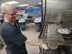  ?? AP PHOTO/JOHN RAOUX ?? In this Thursday, June 7, photo, Tom Mscisz sends a platter of rock shrimp through a broiler at the Dixie Crossroads restaurant in Titusville, Fla. Rock shrimp, once considered trash is celebratin­g 50 years as a popular Florida cuisine.