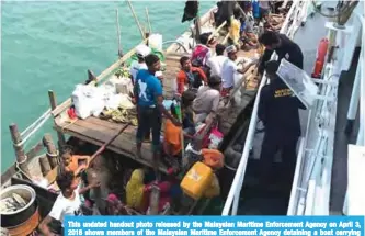  ??  ?? This undated handout photo released by the Malaysian Maritime Enforcemen­t Agency on April 3, 2018 shows members of the Malaysian Maritime Enforcemen­t Agency detaining a boat carrying Rohingya refugees in Malaysian territoria­l waters off the island of...