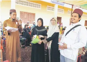  ??  ?? KONGSI: Syafairani membahagi daging korban kepada para muslimah Kampung Prik Bu.