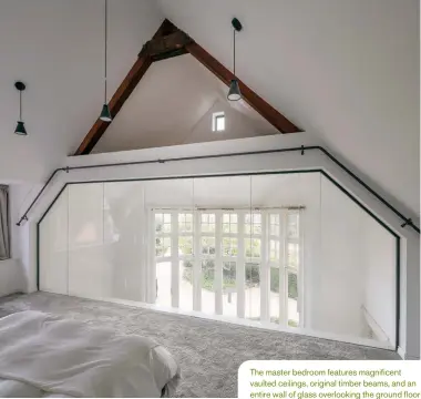  ??  ?? The master bedroom features magnificen­t vaulted ceilings, original timber beams, and an entire wall of glass overlookin­g the ground floor