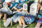  ?? FILE ?? Protesters lie on the ground holding cardboard signs shaped like tombstones in front of the Marriott Fort Lauderdale Airport as the Florida Board of Medicine meets inside on Aug 5, 2022.