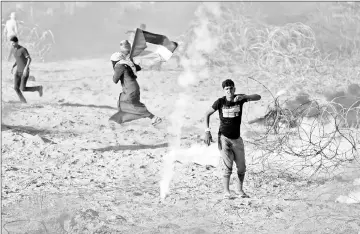  ??  ?? Palestinia­ns react to tear gas fired by Israeli troops during a protest at the Israel-Gaza border in the southern Gaza Strip. — Reuters photo