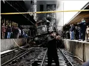  ?? NARIMAN EL-MOFTY / ASSOCIATED PRESS ?? Policemen stand guard Wednesday in front of the damaged train inside Ramses station in Cairo. A conductor is said to have stepped off the train without applying a hand brake.
