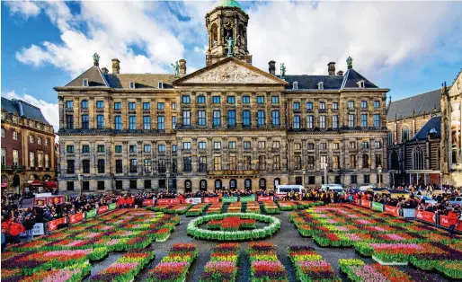  ??  ?? Flower power: Dam Square in front of the Royal Palace of Amsterdam is ablaze with colour at the start of tulip season