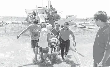  ?? PHOTO FROM PCG-DUMAGUETE VIA JUDY FLORES PARTLOW/PNA ?? Rescuers and Coast Guard personnel carry the injured Chinese scuba diver, who got hit by a pumpboat as he surfaced in the waters off Apo Island in Dauin, Negros Oriental, for transporti­ng to the hospital, where he was however declared dead on arrival.