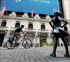  ?? Richard Drew / Associated Press ?? The Fearless Girl statue faces the New York Stock Exchange on July 20. Gains outweighed stock losses on Friday.