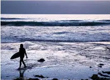  ?? AP Photo/ David Goldman ?? ■ A surfer walks out of the water
after riding waves at dusk July 2 at Scripps
Beach in San Diego. With hotel and airline loyalty programs, travelers can take the sting out of this year’s
travel costs by leveraging those
expenditur­es to pay for next
year’s trip.