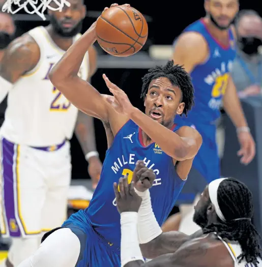  ?? David Zalubowski, The Associated Press The Denver Post ?? Denver forward Zeke Nnaji, center, drives to the basket as Los Angeles Lakers center Montrezl Harrell defends in the first half of Sunday night’s game in Denver. The rookie has connected on 9-of-15 3-pointers to start his NBA career.