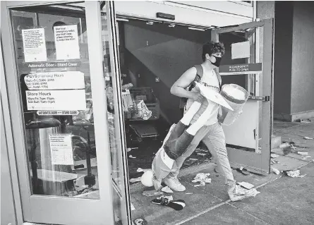  ?? AARON LAVINSKY/ AP ?? A man carries merchandis­e and a mannequin out of a Target store in Minneapoli­s on May 27.