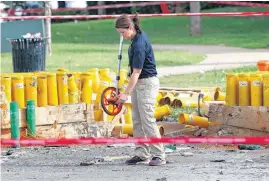  ??  ?? Edmond Police Technical Investigat­or Melissa Taft searches for evidence at the scene of a fireworks display explosion on July 5, which caused injury to one person and damage to a building at the Edmond LibertyFes­t. Authoritie­s said Thursday they were...