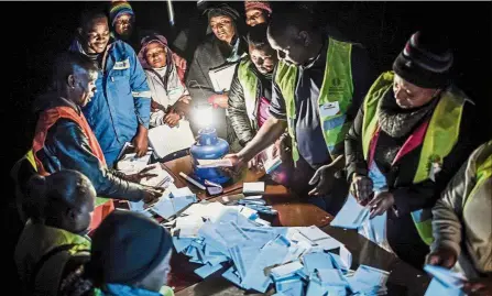  ?? AFP ?? Painstakin­g task: Observers checking the tally of votes at a polling station in the suburb of Mbare in the capital Harare. —