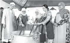  ?? Bernama photo ?? Tunku Azizah (second left) and princess Puteri Jihan (second right) accompanie­d by Wan Azizah (centre) helping to prepare bubur lambuk. -