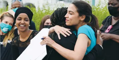  ?? (Elizabeth Frantz/Reuters) ?? US REPRESENTA­TIVES Cori Bush and Alexandria Ocasio-Cortez embrace as Rep. Ilhan Omar looks on before the start of a news conference in Washington last week.